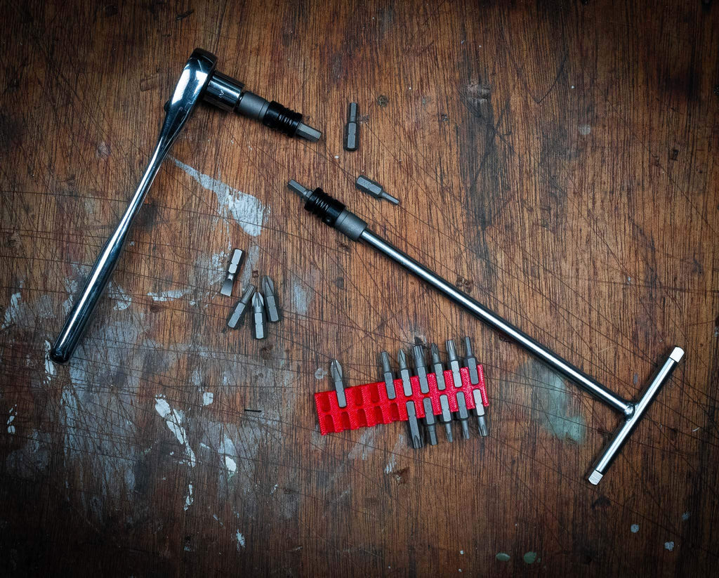 1/4" adaptor with quick-release bit chuck and various tool bits on a wooden surface.